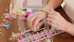 Closeup of woman makes braslets with elastic bands