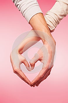 Closeup of woman and man hands showing heart shape