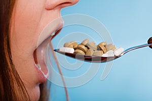 Closeup of woman mouth eating painkiller pills.