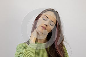 Closeup woman neck and shoulder pain and injury. Health care and medical concept. Girl with Her Eyes Closed in a Green Sweater on