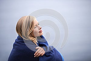 Closeup, woman and outdoor with blanket for holiday with smile, wellness and contemplate for leisure. Vacation, reflect