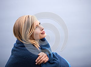 Closeup, woman and outdoor with blanket for thinking with smile, wellness and contemplate for leisure. Holiday, reflect