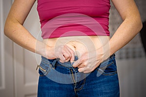 Closeup of woman pinching belly fat.