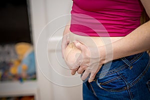 Closeup of woman pinching belly fat.