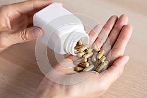 Closeup woman pouring herb capsules from bottle to another hand