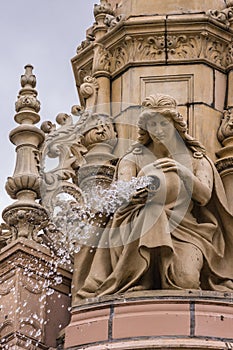 Closeup of woman pouring water, Doulton Fountain, Glasgow Scotland UK.