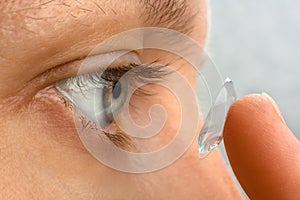 Closeup of woman putting contact lens in her eye