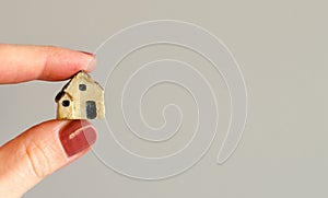 Closeup of woman`s fingers holding tiny plastic house photo
