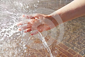 Closeup of woman`s hand cooling in a water fountain