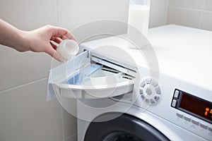 Closeup of a woman's hand pouring liquid fabric softener