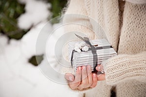 Closeup of woman`s hands holding a nice Christmas present. Outdoors. Celebration. Holidays, gifts and winter concept