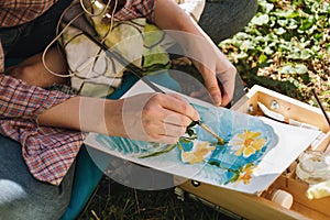 Closeup of woman`s hands paiting in oils bright flowers