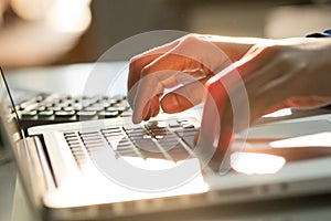 Closeup woman`s hands typing on a laptop with sunlight. Selective focus