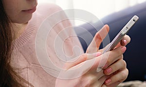 Closeup woman`s hands typing a message. Unrecognizable woman in pink sweater with pink manicure.