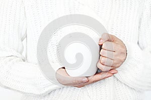 Closeup of woman`s hands in white knitted sweater holding cup of coffee. Blank mug mock-up scene. Chritsmas winter