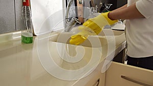 Closeup on woman`s hands in yellow protective gloves cleaning kitchen furniture