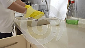 Closeup on woman`s hands in yellow rubber protective gloves washing plates