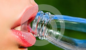 Closeup of woman's lips drinking. Beautiful female lips, bottle with soda. Cute fashion summer look with bottle of