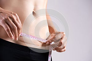 Closeup of woman showing on her belly dark scar from a cesarean section with measuring tape. Healthcare concept