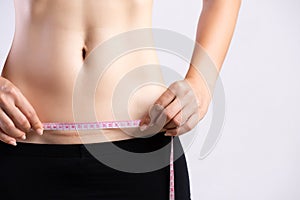 Closeup of woman showing on her belly dark scar from a cesarean section with measuring tape. Healthcare concept