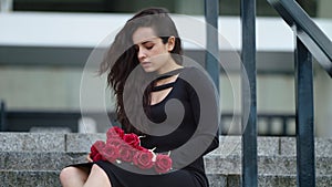 Closeup woman sitting in dress at street. Woman crying on stairs outdoors