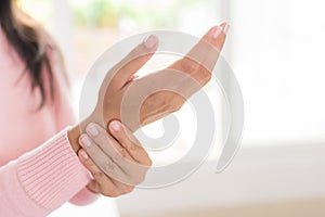 Closeup woman sitting on sofa holds her wrist hand injury