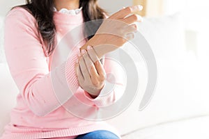 Closeup woman sitting on sofa holds her wrist hand injury