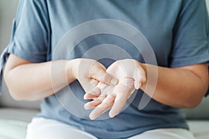 Closeup of woman sitting on sofa holds her wrist. hand injury, feeling pain. Health care and medical concept