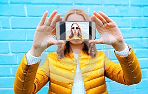 Closeup woman takes picture self portrait on smartphone on blue