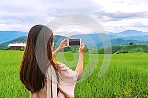 Closeup of woman traveler using smartphone take a photo at rice field terraces in the morning