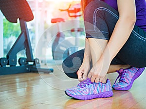 closeup of woman tying shoe laces. Female sport fitness runner getting ready for jogging in gym room