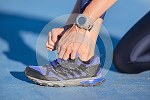 Closeup of woman tying shoe laces. Female sport fitness runner getting ready for jogging outdoors