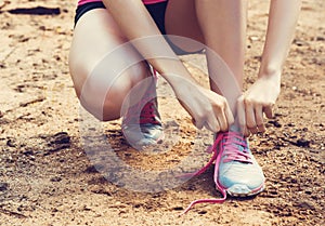 Closeup of woman tying shoe laces. Female sport fitness runner getting ready for jogging outdoors on forest path i