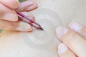 Closeup asian woman use tweezer for plucking hairy leg