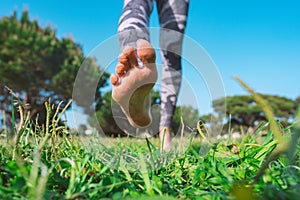 Closeup of woman walking barefoot on the green grass. Barefoot running in the park