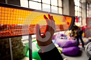 Closeup of woman warming hands at infrared heater