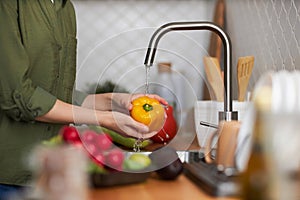 Closeup of woman washing fresh ripe vegetables in kitchen