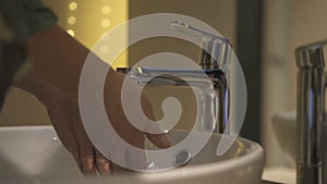 Closeup of woman washing hands in bathroom sink