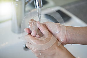 Closeup of a woman washing hands with soap lather over bathroom sink. Girl cleaning hand photo
