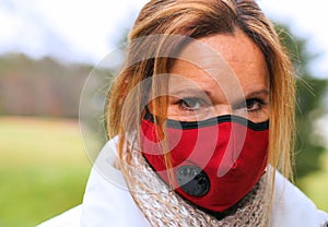 A closeup of a woman wearing a red antivwoman wearing virus protection mask