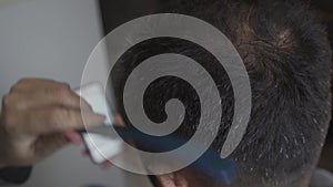 Closeup on woman who cutting her husband hair sitting and looking at smartphone browsing social networks at home during