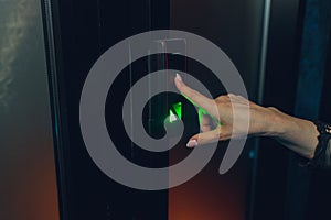 Closeup of a woman& x27;s finger entering password code on the smart digital touch screen keypad entry door lock in front of