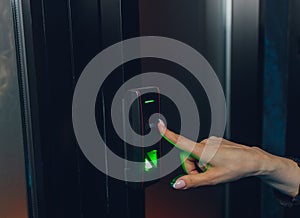 Closeup of a woman& x27;s finger entering password code on the smart digital touch screen keypad entry door lock in front of