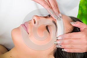 Closeup womans face receiving facial hair wax treatment, beauty and fashion concept