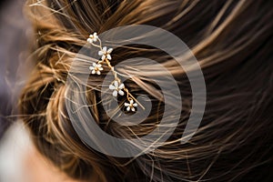 closeup of a womans hair styled with a floral hairpin accessory