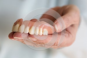 Closeup of womans hand holding a teeth denture photo