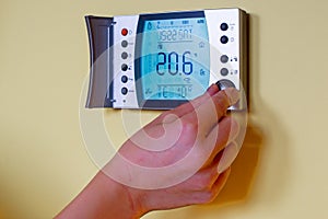Closeup of a womans hand setting the room temperature on a mode