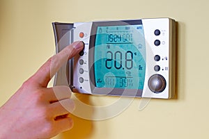 Closeup of a womans hand setting the room temperature on a mode