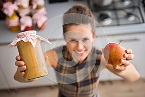 Closeup of womans hands holding apple sauce and fresh apple