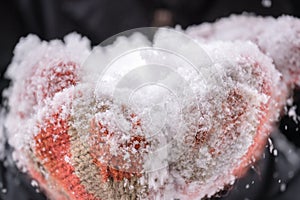 Closeup of womans hands wearing orange and beige knitted mittens